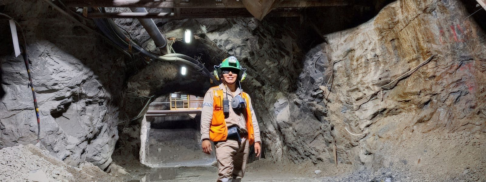 A mine worker in high visibility gear and hard hat at an underground development end, the kind of environment where a tracking tag must be intrinsically safe.